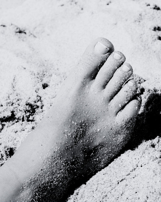 Black and white image of a foot in the sand