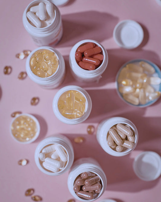 Bottles of various medical food supplements on a pink table