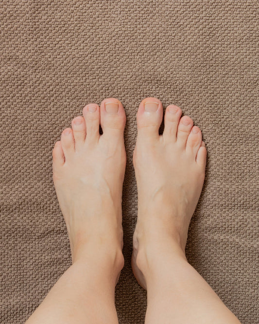 A person's feet standing on a brown carpet
