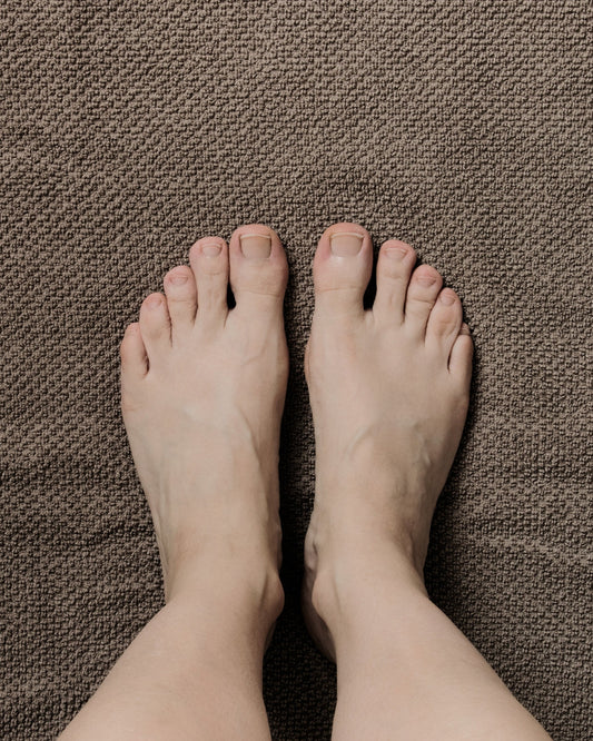 A person's feet standing on brown upholstery