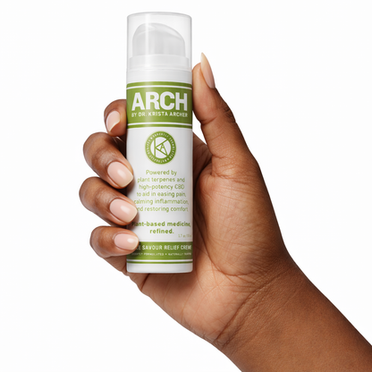 Hand holding a bottle of Arch Sole Savour Relief Creme with a white background